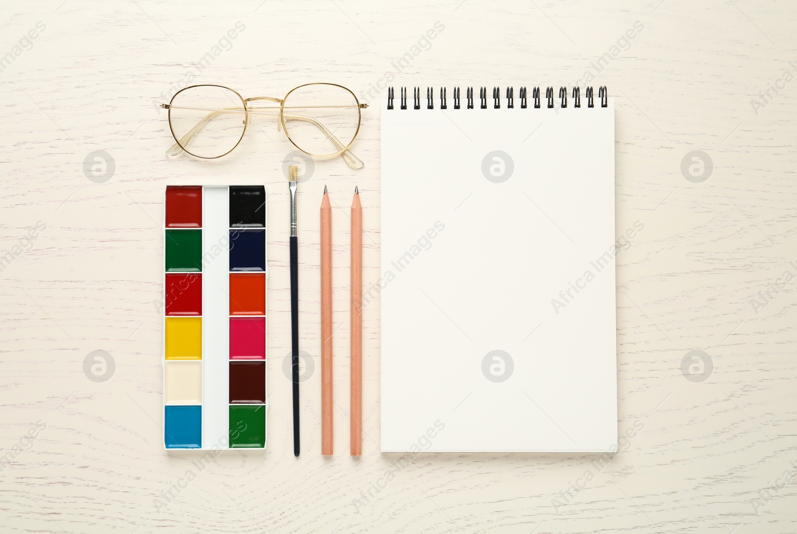 Photo of Flat lay composition with blank sketchbook on white wooden table. Space for text