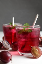 Photo of Delicious grape soda water and berries on white table. Refreshing drink