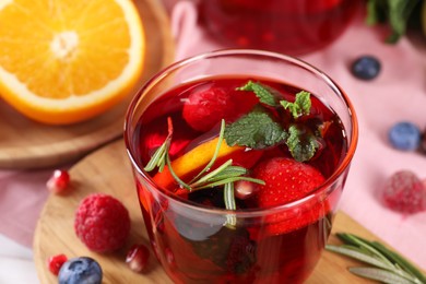 Photo of Glass of delicious sangria, fruits and berries on table, closeup