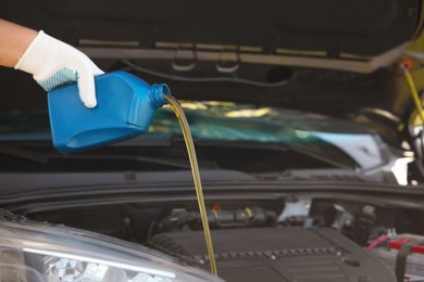 Photo of Man pouring motor oil from blue container, closeup. Space for text