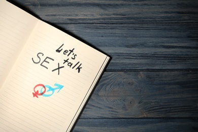 Photo of Notebook with phrase "LET'S TALK SEX" and gender symbols on dark wooden background, top view. Space for text