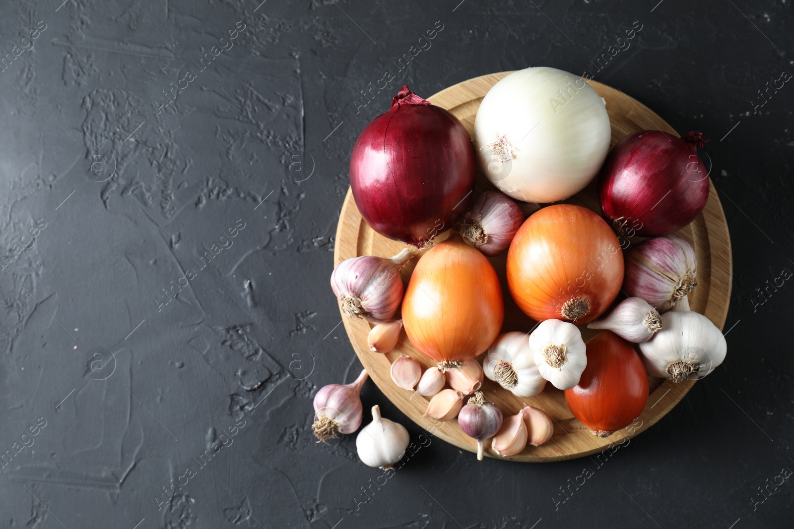 Photo of Fresh raw garlic and onions on black table, top view. Space for text