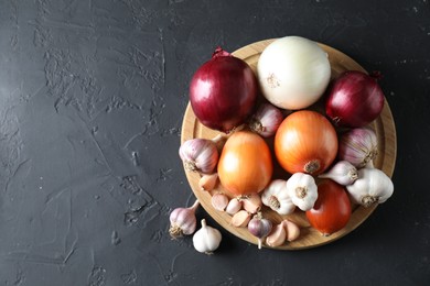 Fresh raw garlic and onions on black table, top view. Space for text