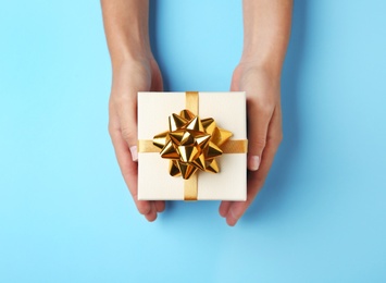 Photo of Woman holding beautiful gift box on blue background, top view