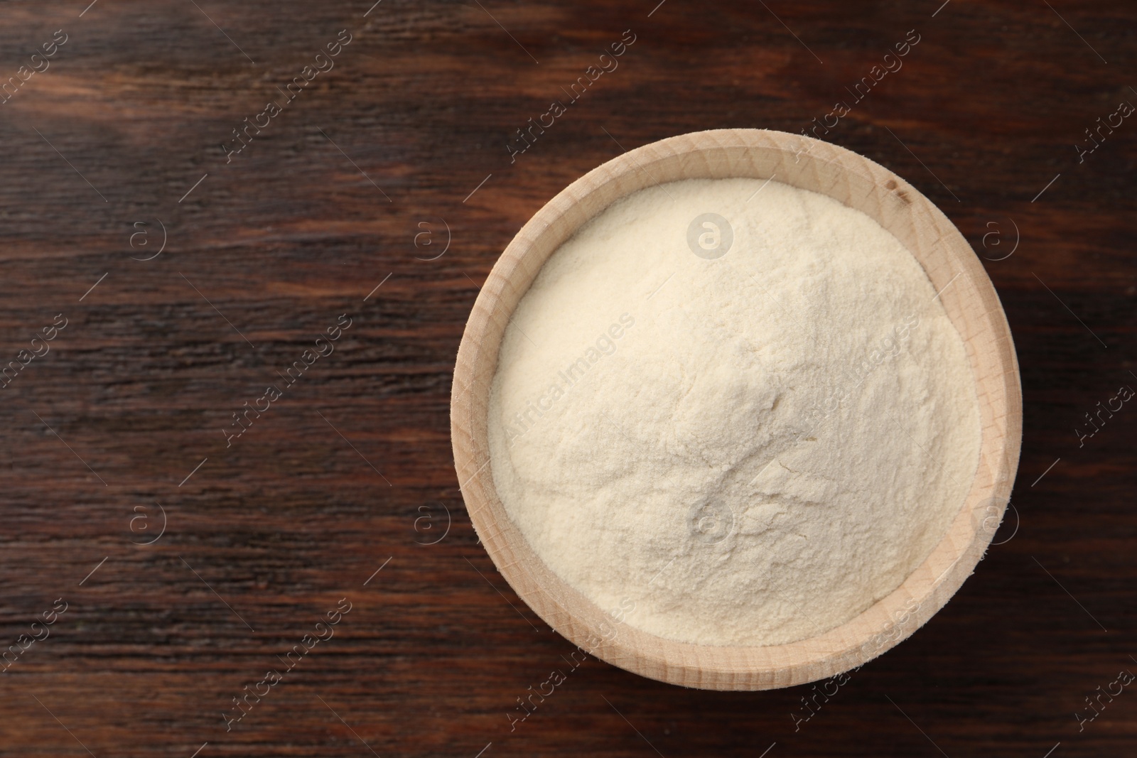 Photo of Bowl of agar-agar powder on wooden table, top view. Space for text