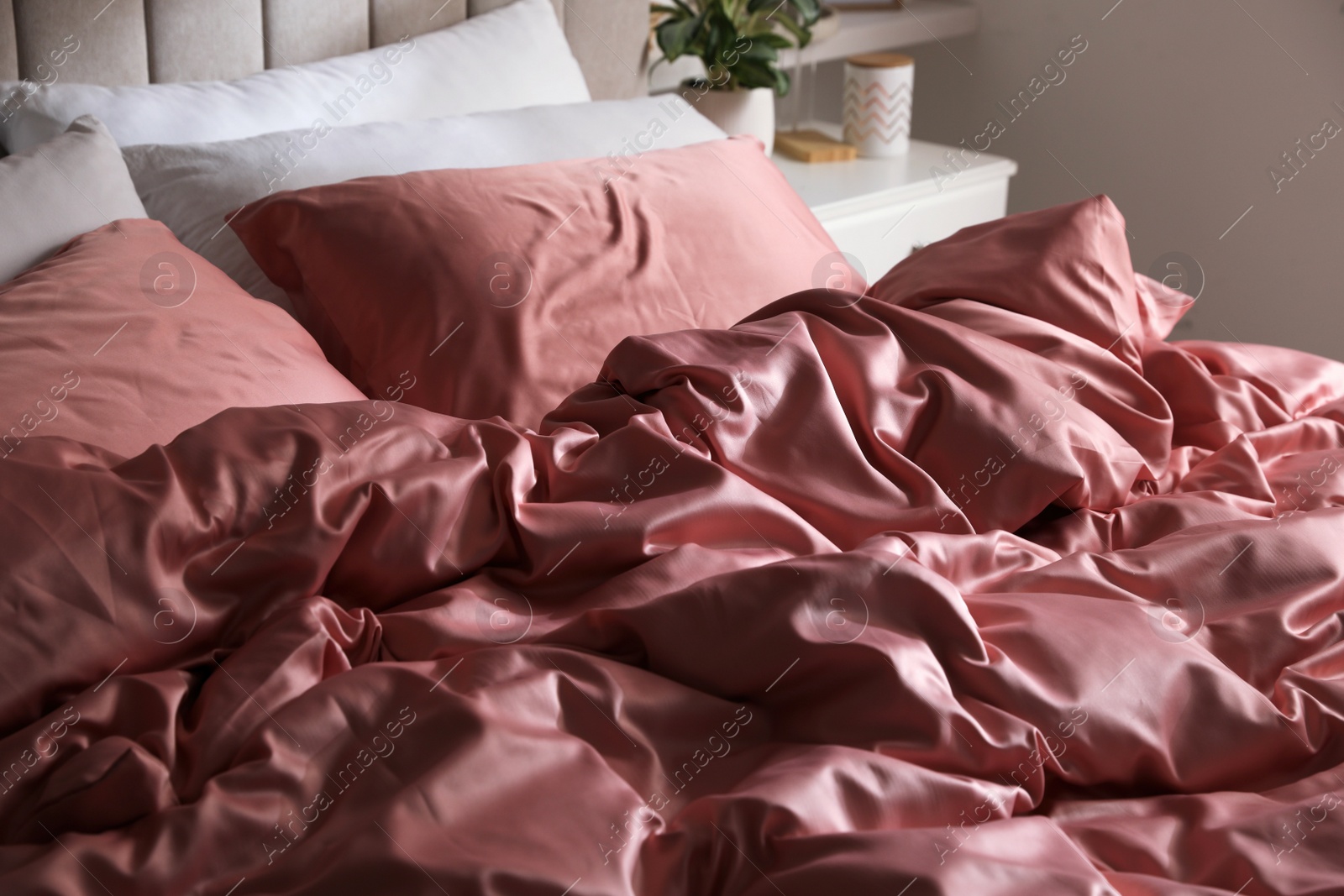 Photo of Bed with beautiful silk linens indoors, closeup