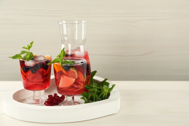 Photo of Delicious Red Sangria and ingredients on white wooden table, space for text