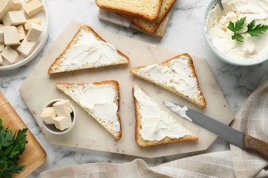 Photo of Delicious toasts with tofu cream cheese and parsley on white marble table, flat lay