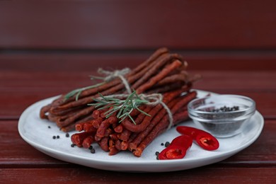 Photo of Tasty dry cured sausages (kabanosy) and ingredients on wooden table, closeup