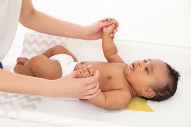 Photo of Mother and her cute child on changing table. Baby massage and exercises