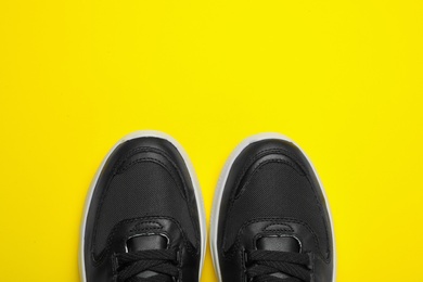 Photo of Pair of stylish shoes on yellow background, top view. Space for text