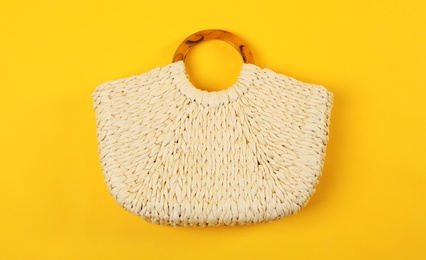 Stylish woman's straw bag on yellow background, top view