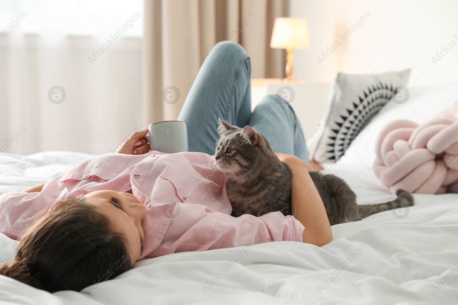 Photo of Young woman with cute cat on bed at home. Pet and owner