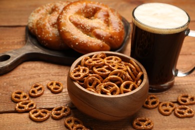 Photo of Tasty freshly baked pretzels, crackers and mug of beer on wooden table, closeup