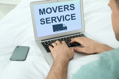 Image of Man using laptop to order movers service at home, closeup