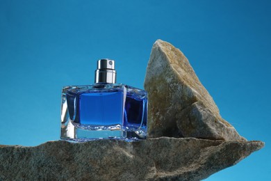 Photo of Stylish presentation of luxury men`s perfume on stones against light blue background