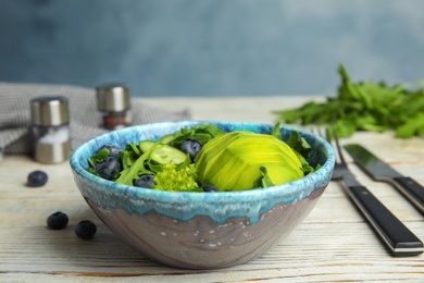 Photo of Delicious avocado salad with blueberries in bowl on white wooden table