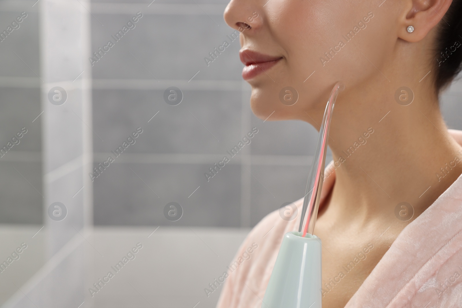 Photo of Woman using high frequency darsonval device in bathroom, closeup. Space for text