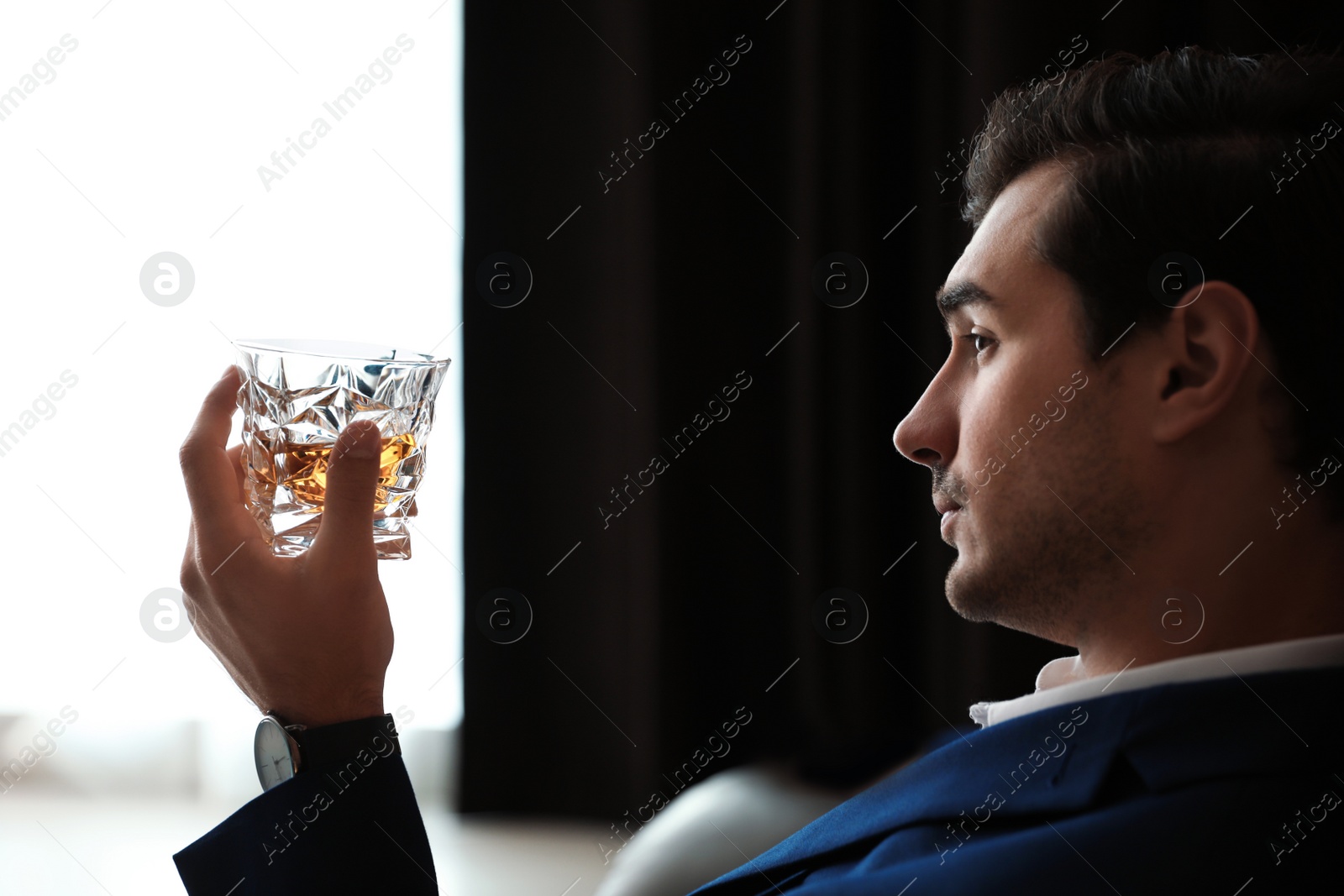 Photo of Young man with glass of whiskey indoors