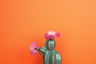 Photo of Trendy cactus shaped ceramic vase with flowers on color background