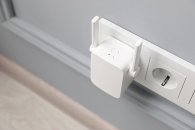 Photo of Wireless Wi-Fi repeater on light grey wall, above view