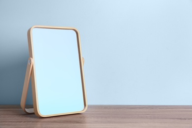 Photo of Stylish mirror on table near light wall