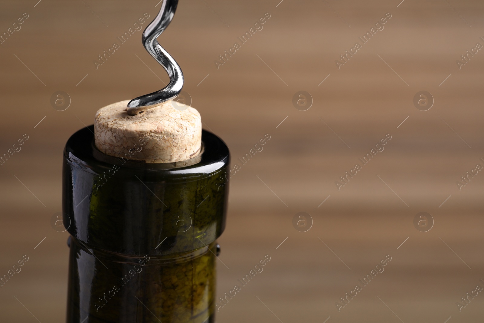 Photo of Opening wine bottle with corkscrew on color background, closeup. Space for text