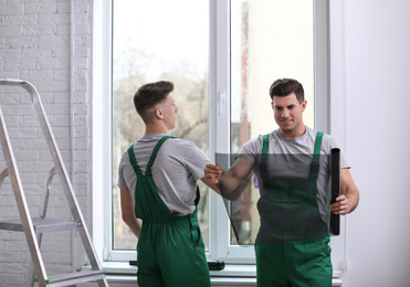 Professional workers tinting window with foil indoors