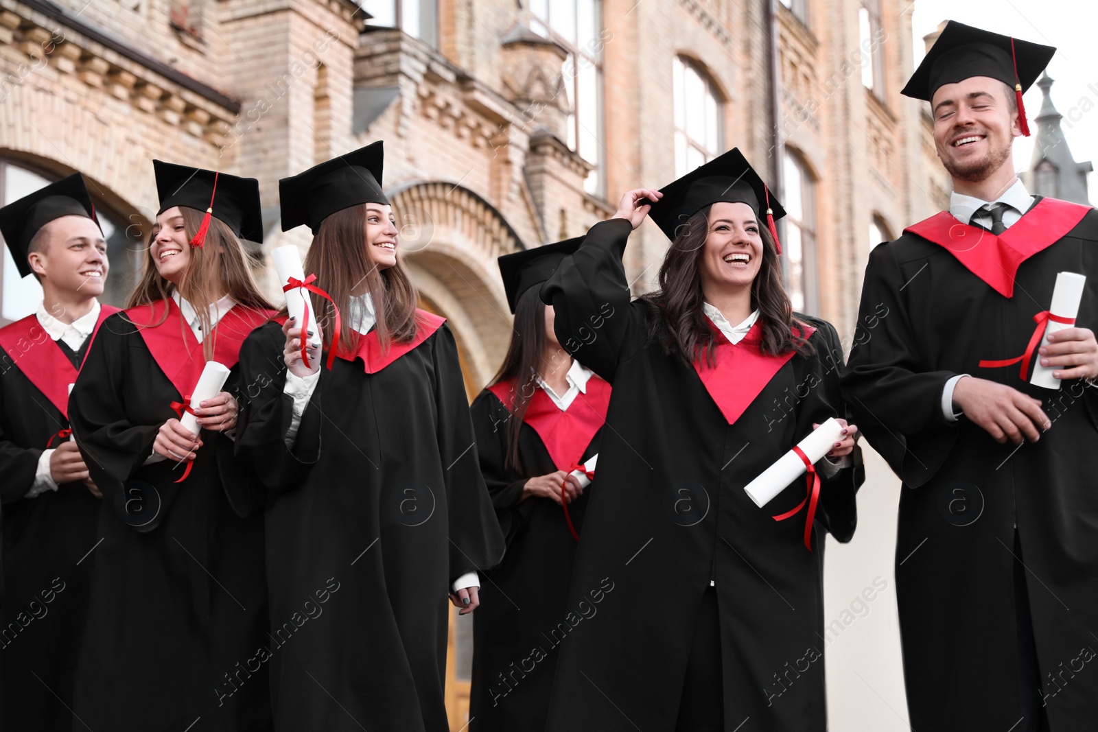 Photo of Happy students with diplomas outdoors. Graduation ceremony