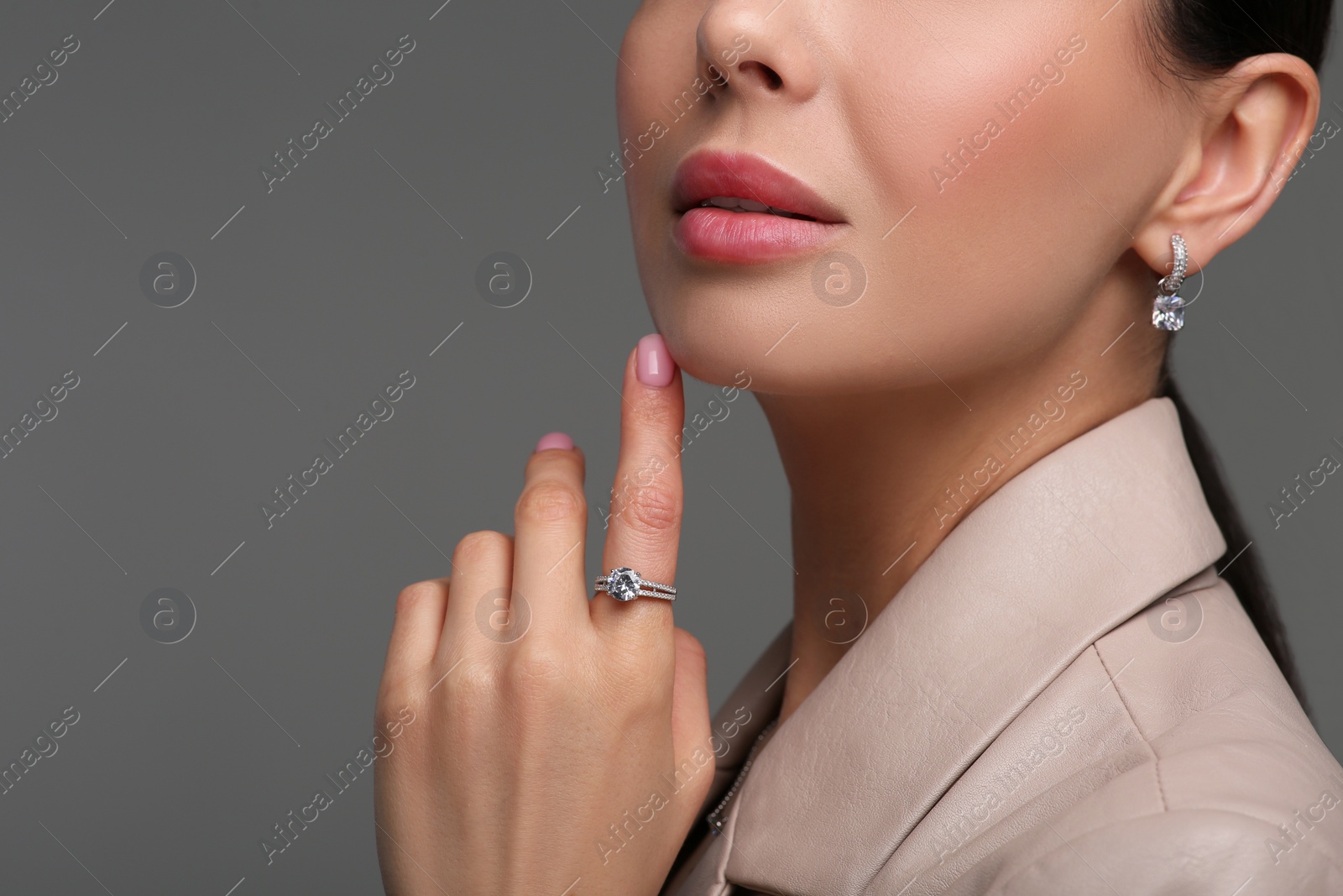 Photo of Young woman with elegant jewelry on dark grey background, closeup