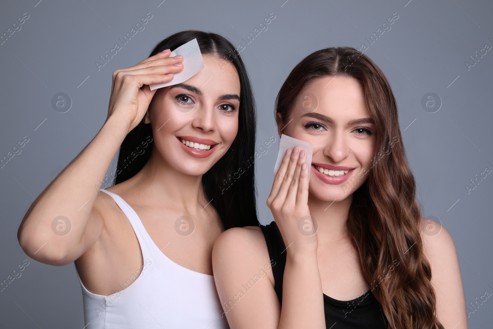 Photo of Beautiful women using mattifying wipes on grey background