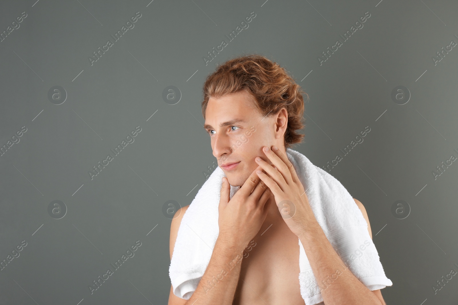 Photo of Young man touching his soft skin after shaving on gray background