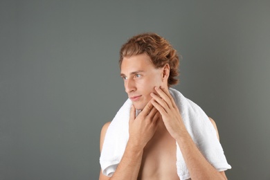 Photo of Young man touching his soft skin after shaving on gray background