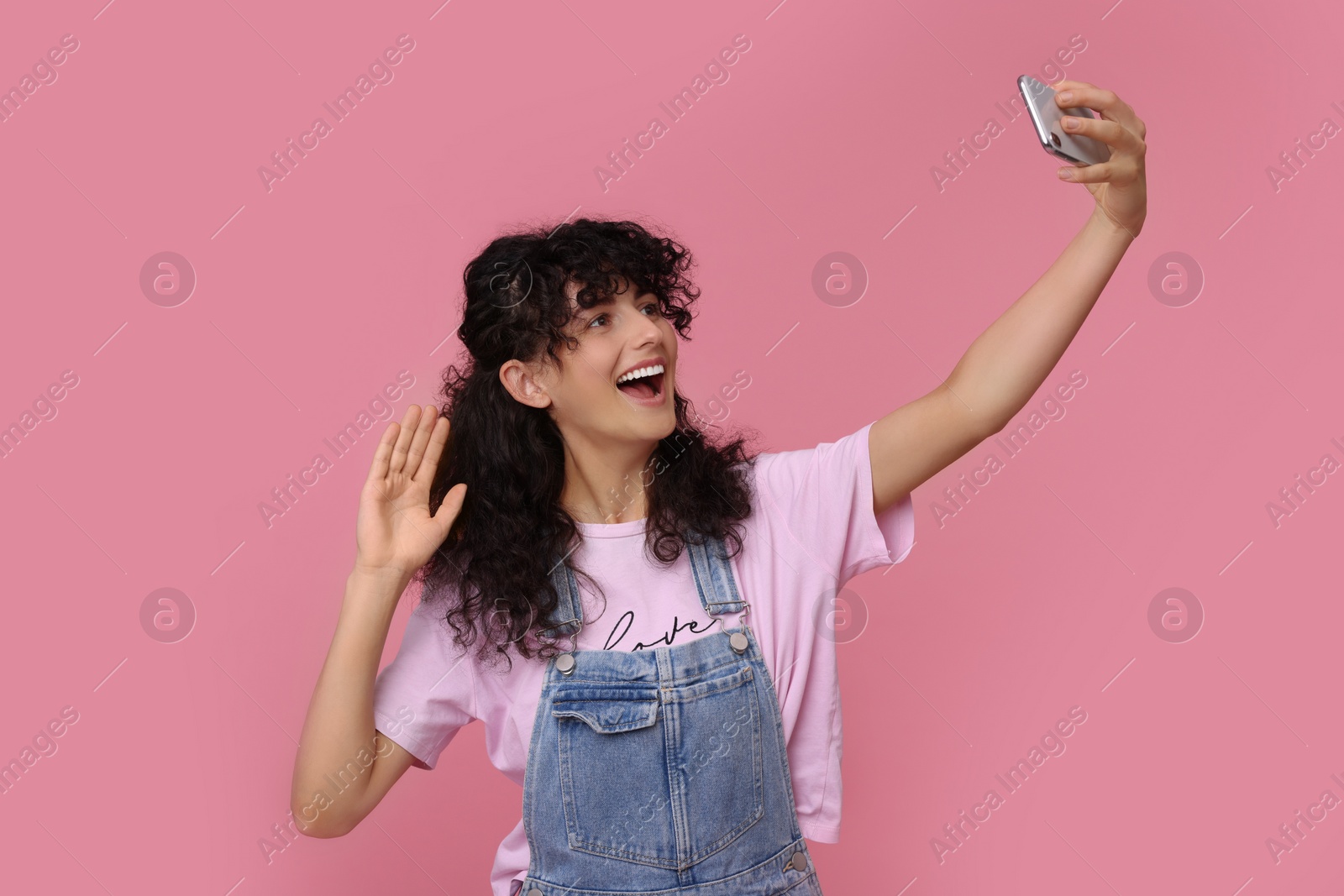 Photo of Beautiful young woman taking selfie on pink background