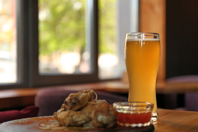 Photo of Delicious hot BBQ wings and beer served on table