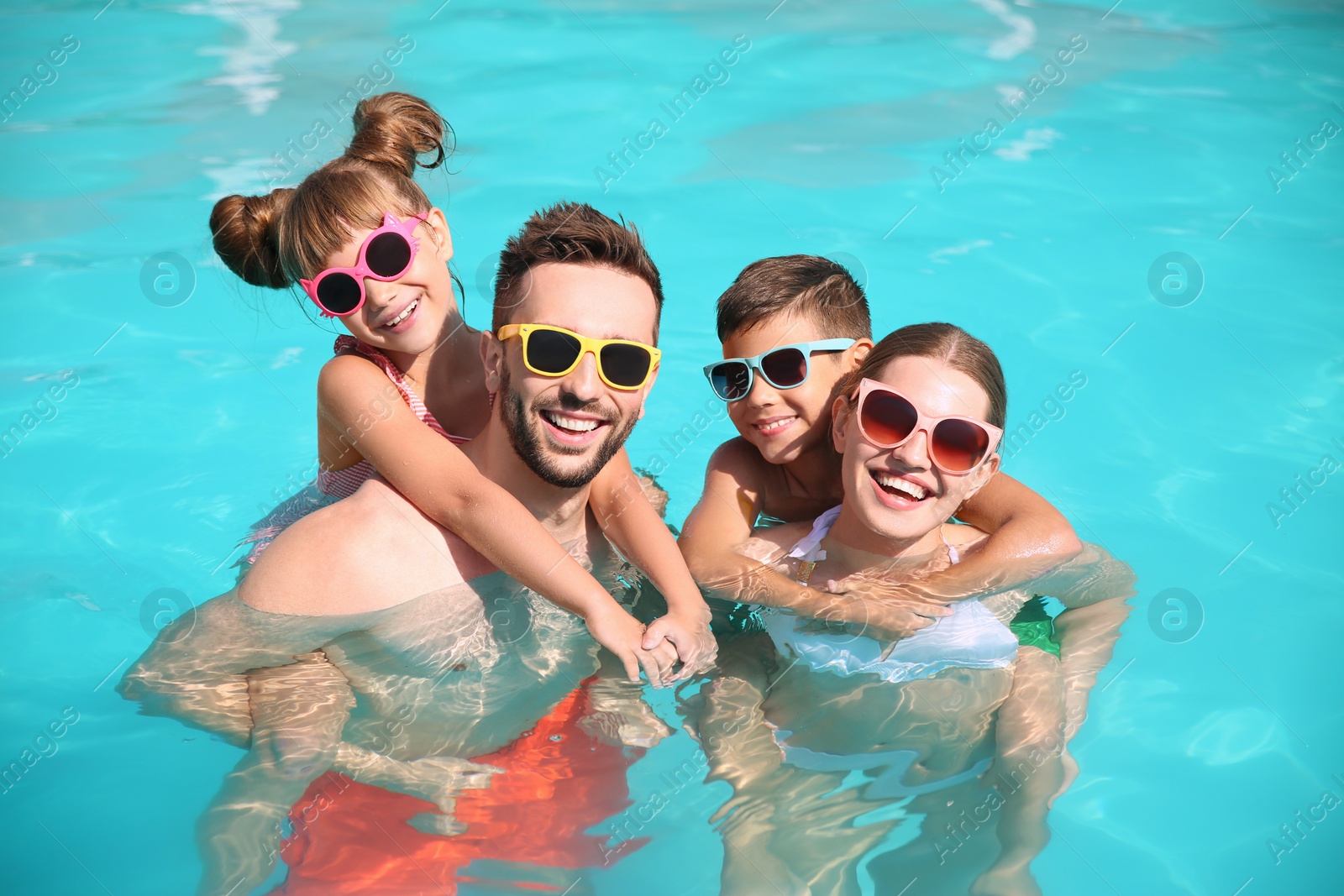 Photo of Happy family in swimming pool on sunny day