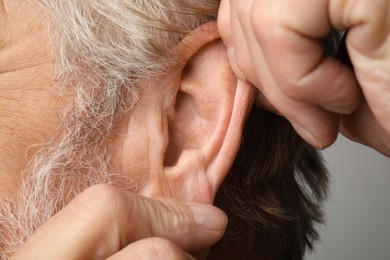 Photo of Man touching his ear on light grey background, closeup
