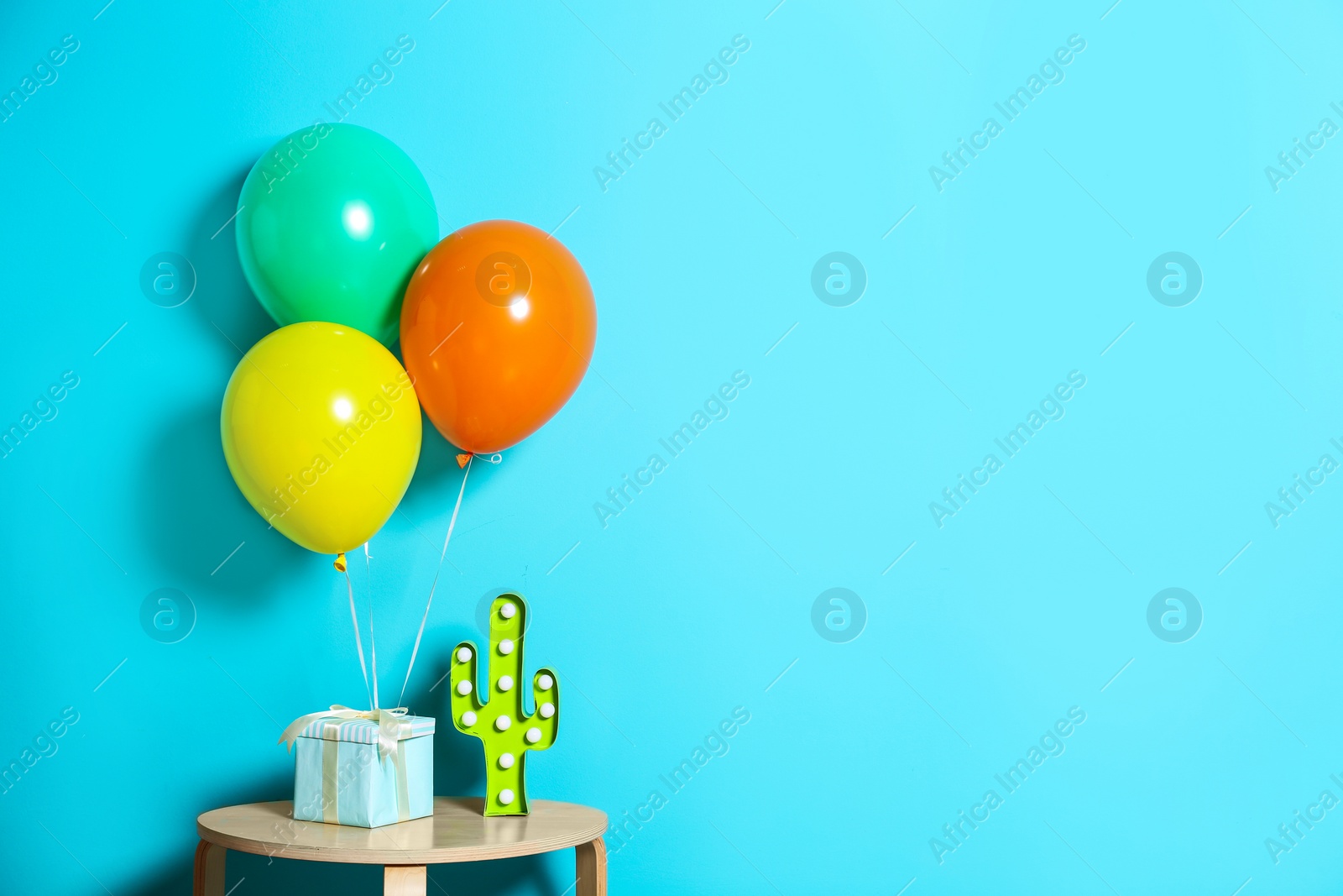 Photo of Gift box and balloons against color background