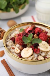 Photo of Delicious oatmeal with freeze dried berries, banana, nuts and mint on table, closeup