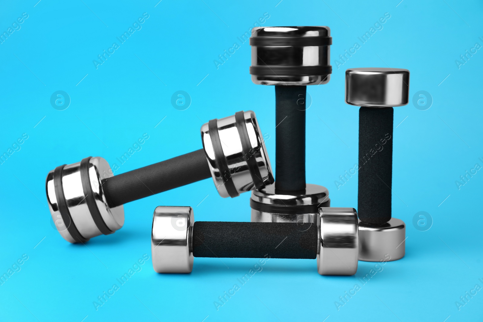 Photo of Many stylish dumbbells on light blue background