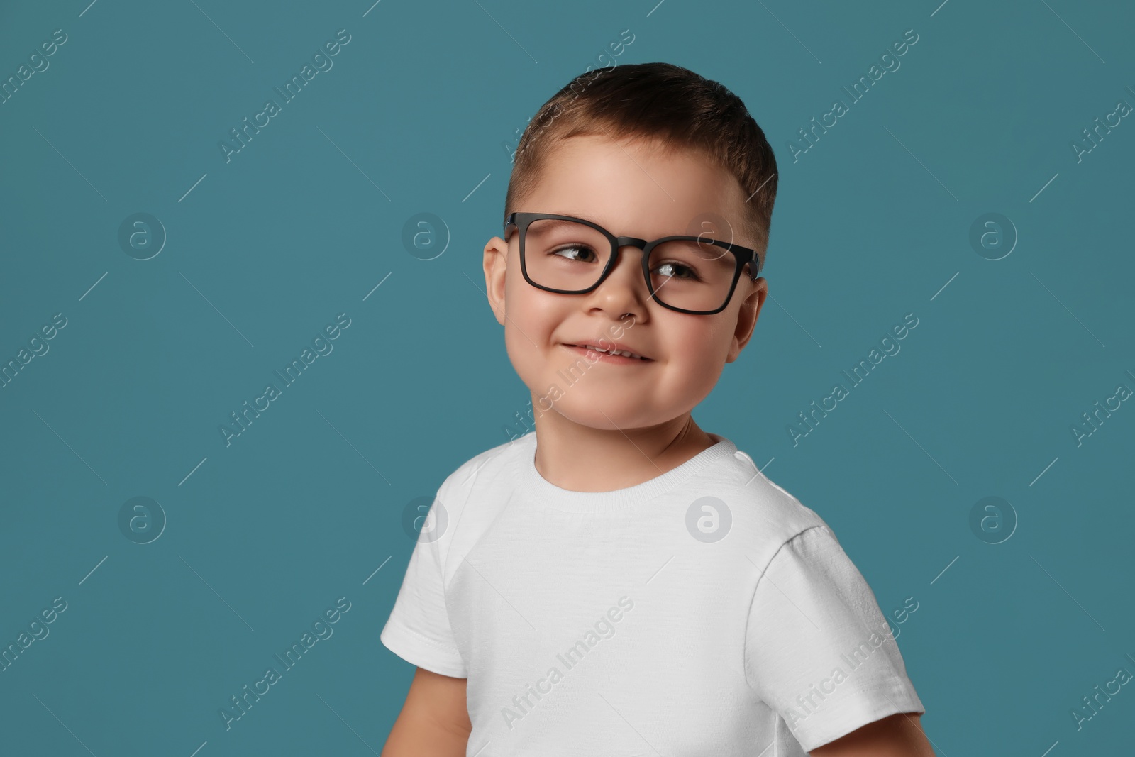 Photo of Cute little boy in glasses on light blue background