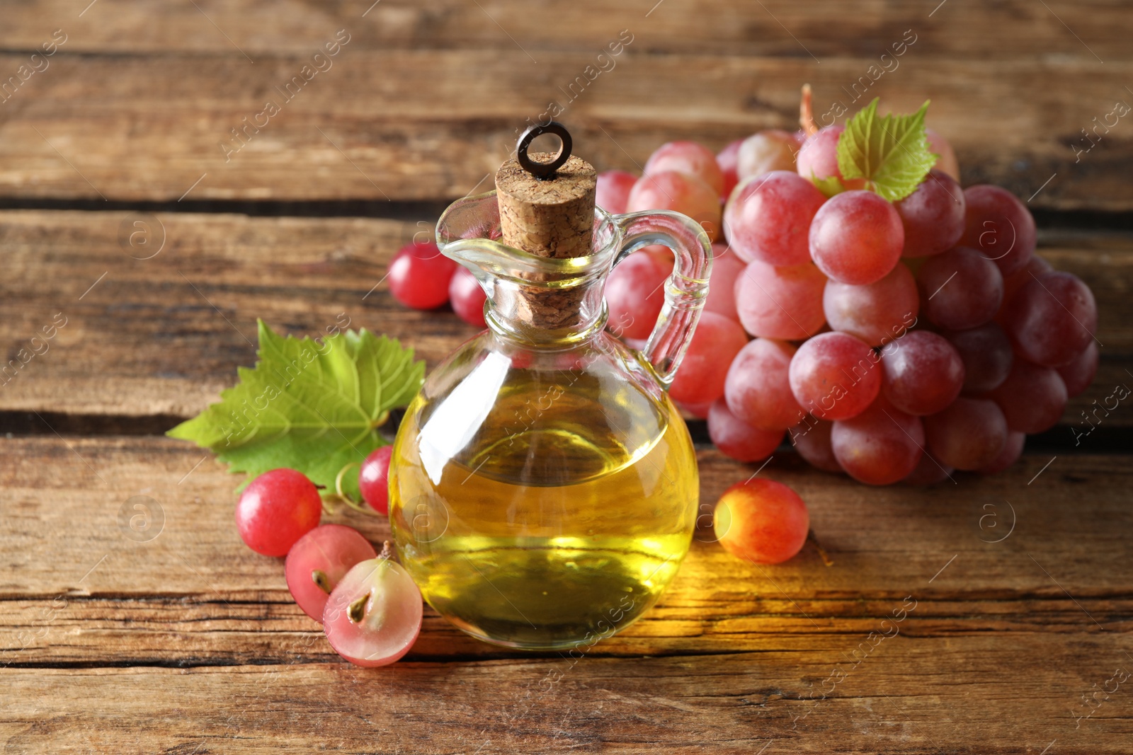 Photo of Jug of natural grape seed oil on wooden table. Organic cosmetic