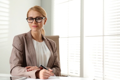 Photo of Young businesswoman sitting at table in office