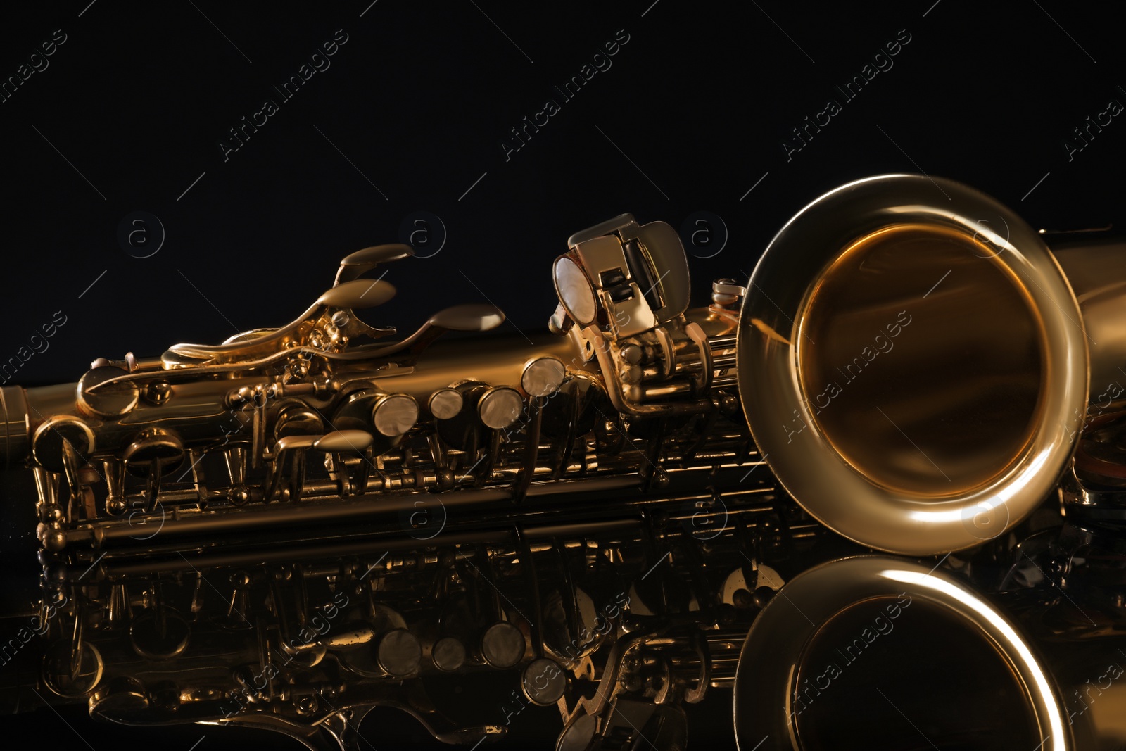 Photo of Beautiful saxophone on black background, closeup. Musical instrument