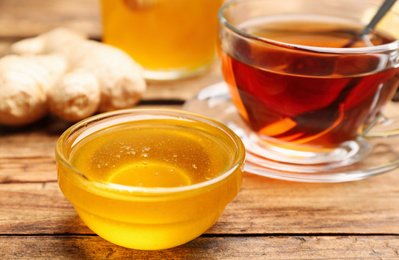 Photo of Tasty honey and tea on wooden table, closeup