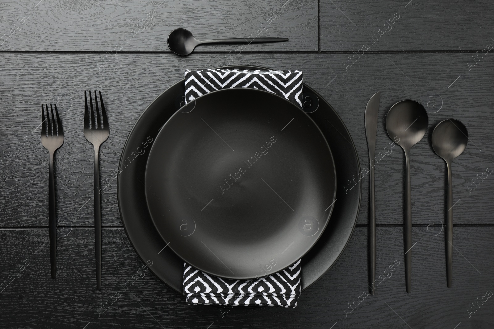 Photo of Stylish setting with cutlery and plates on black wooden table, flat lay