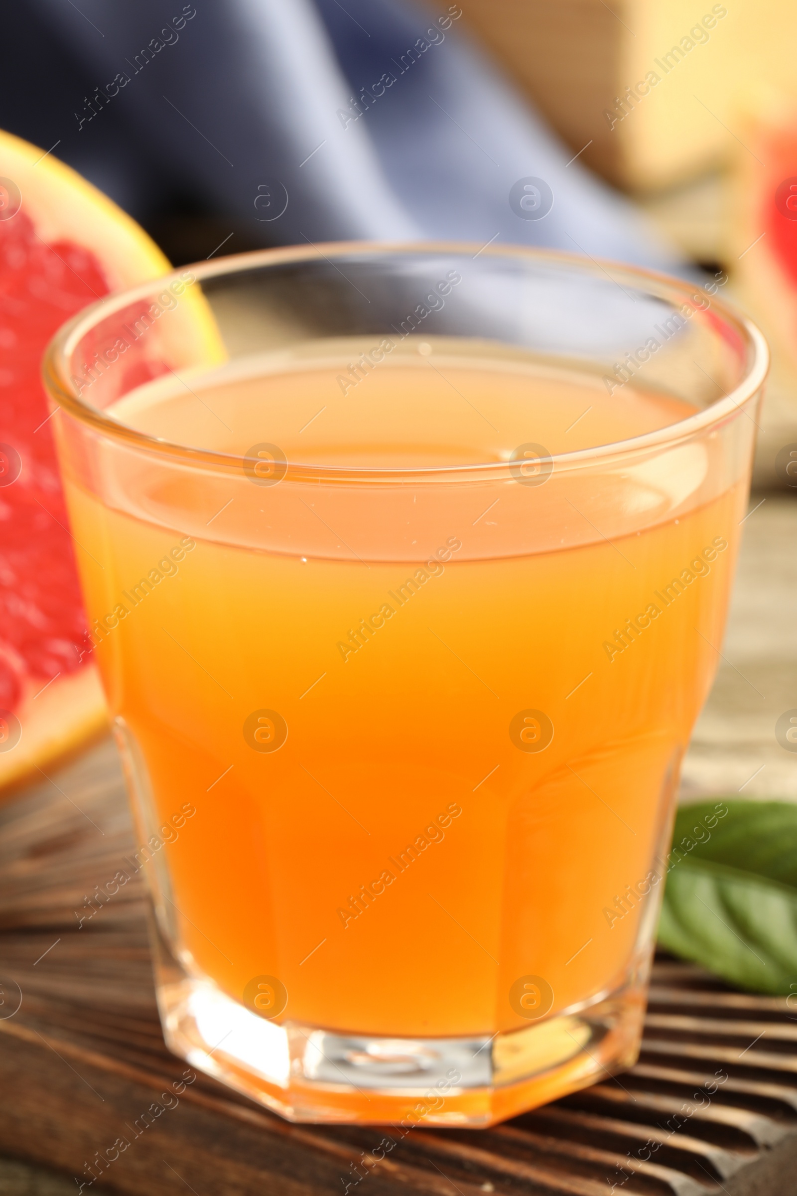 Photo of Glass of delicious grapefruit juice on wooden table, closeup