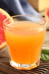 Photo of Glass of delicious grapefruit juice on wooden table, closeup