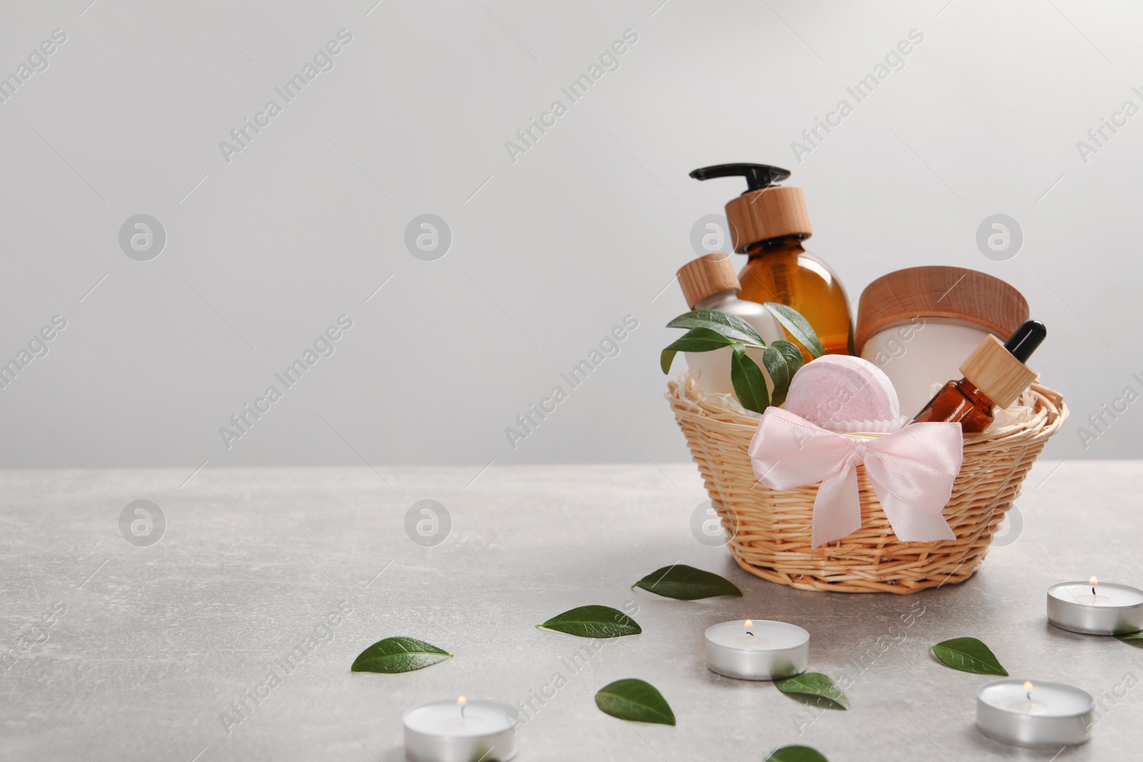 Photo of Spa gift set of different luxury products in wicker basket on grey table, space for text