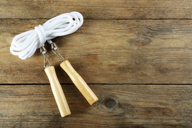 Photo of Skipping rope on wooden table, top view. Space for text